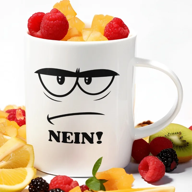 Weiße Kaffeetasse mit einem genervten Comic-Gesicht, das dicke Augenbrauen und einen schmalen Strichmund zeigt, ergänzt durch das groß geschriebene Wort „NEIN!“.