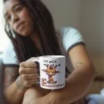 Weiße Kaffeetasse mit einer Illustration einer wütenden Giraffe mit verschränkten Armen und dem lustigen Spruch „Ich guck wie ich will – das nennt man Fressefreiheit“.