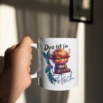 Weiße Kaffeetasse mit einer Illustration eines mürrischen Hochlandrinds im Karohemd und dem Wortspiel-Schriftzug „Das ist ja YAKtastisch“.