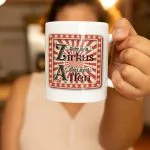 Weiße Kaffeetasse mit einem rot-weiß gestreiften Zirkus-Logo und dem Spruch „Nicht mein Zirkus, nicht meine Affen“ in nostalgischer Schrift.
