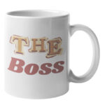 Weiße Keramiktasse mit seitlichem Henkel und dem mehrfarbigen Schriftzug „THE BOSS“ in Retro-Buchstaben auf der Vorderseite.