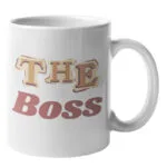 Weiße Keramiktasse mit seitlichem Henkel und dem mehrfarbigen Schriftzug „THE BOSS“ in Retro-Buchstaben auf der Vorderseite.